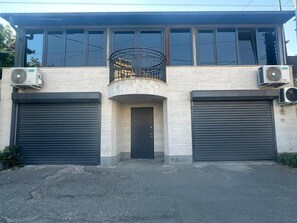 A two-story building with a balcony, two large garage doors, and two air conditioning units. - Alikhanyan House (Yerevan)
