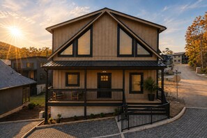 A two-story wooden house with a balcony, a front door, and a garage. - LUX Cabin/1mi to Parkway/Golf Suite/Indoor Pool (Pigeon Forge)