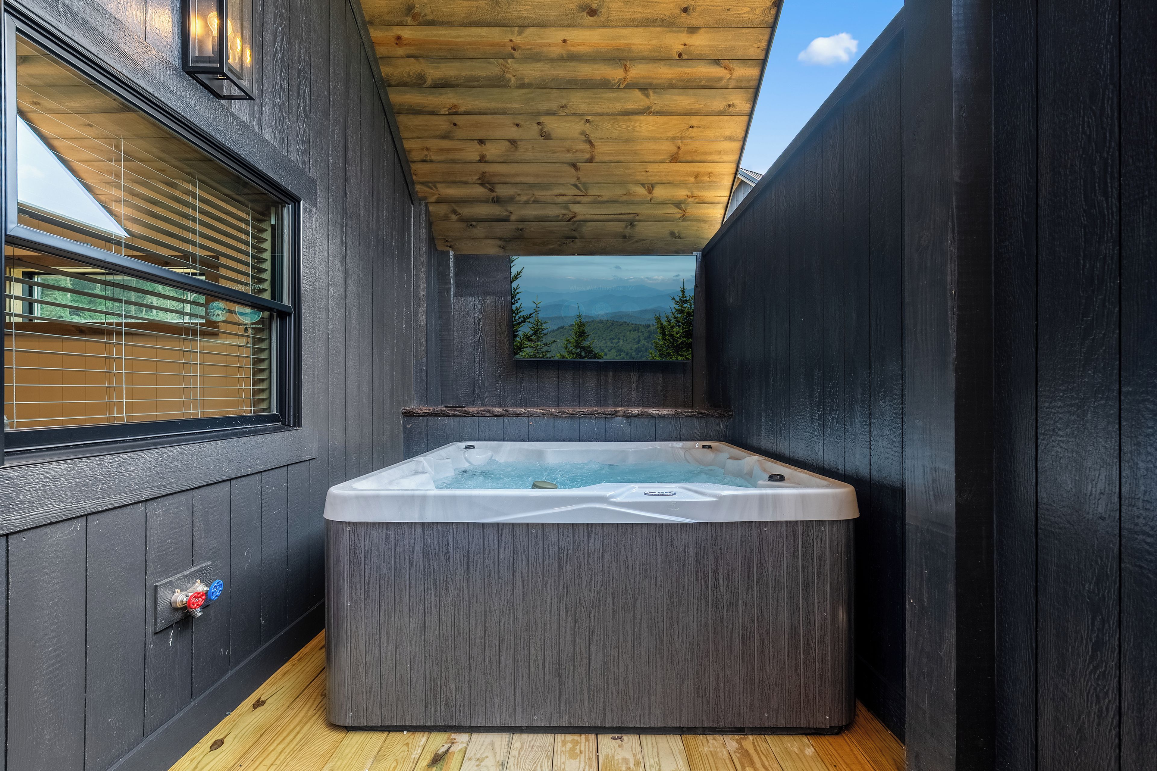 Un jacuzzi en una cabaña de madera con ventana que da a un paisaje montañoso.