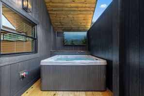 Un jacuzzi en una cabaña de madera con ventana que da a un paisaje montañoso.
