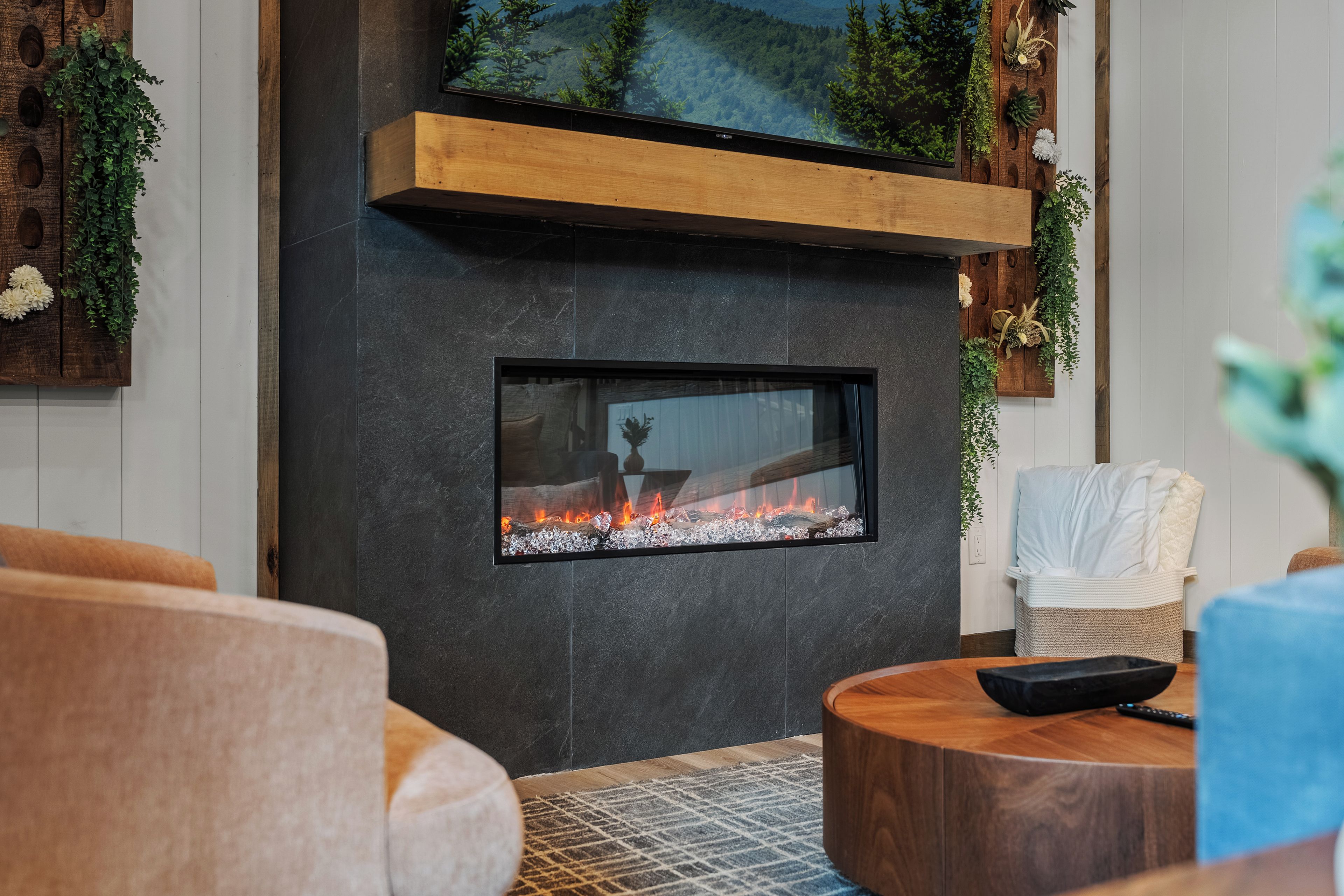 Una sala de estar moderna con chimenea, muebles de madera y plantas decorativas.