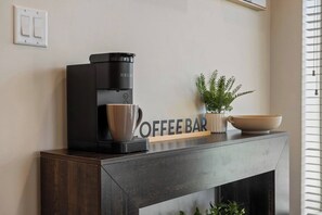 A modern coffee maker on a dark wooden console table with a 'COFFEE BAR' sign, a potted plant, and a bowl. - Sleeps 18/Rooftop/Golf Suite/Indoor Pool/Hot Tub (Pigeon Forge)