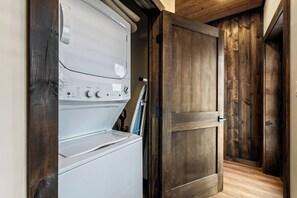 A laundry area with a white washer and dryer, wooden doors, and a wooden floor. - Sleeps 18/Rooftop/Golf Suite/Indoor Pool/Hot Tub (Pigeon Forge)