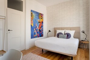 Ein Schlafzimmer mit einem Bett, einem Gemälde, einer Lampe und einem Sessel.
