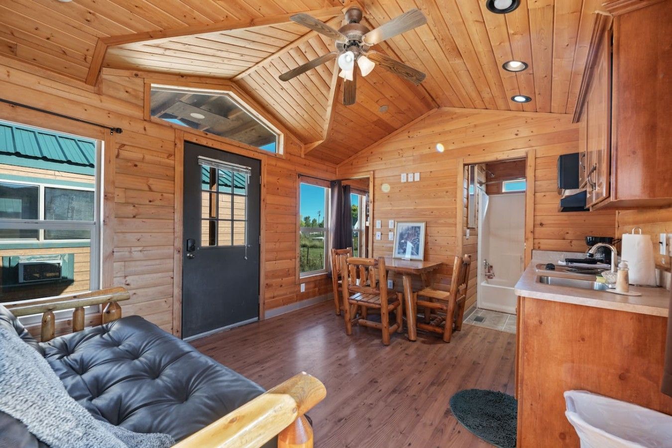 A cozy cabin interior with a dining area, a sofa, and a kitchen.