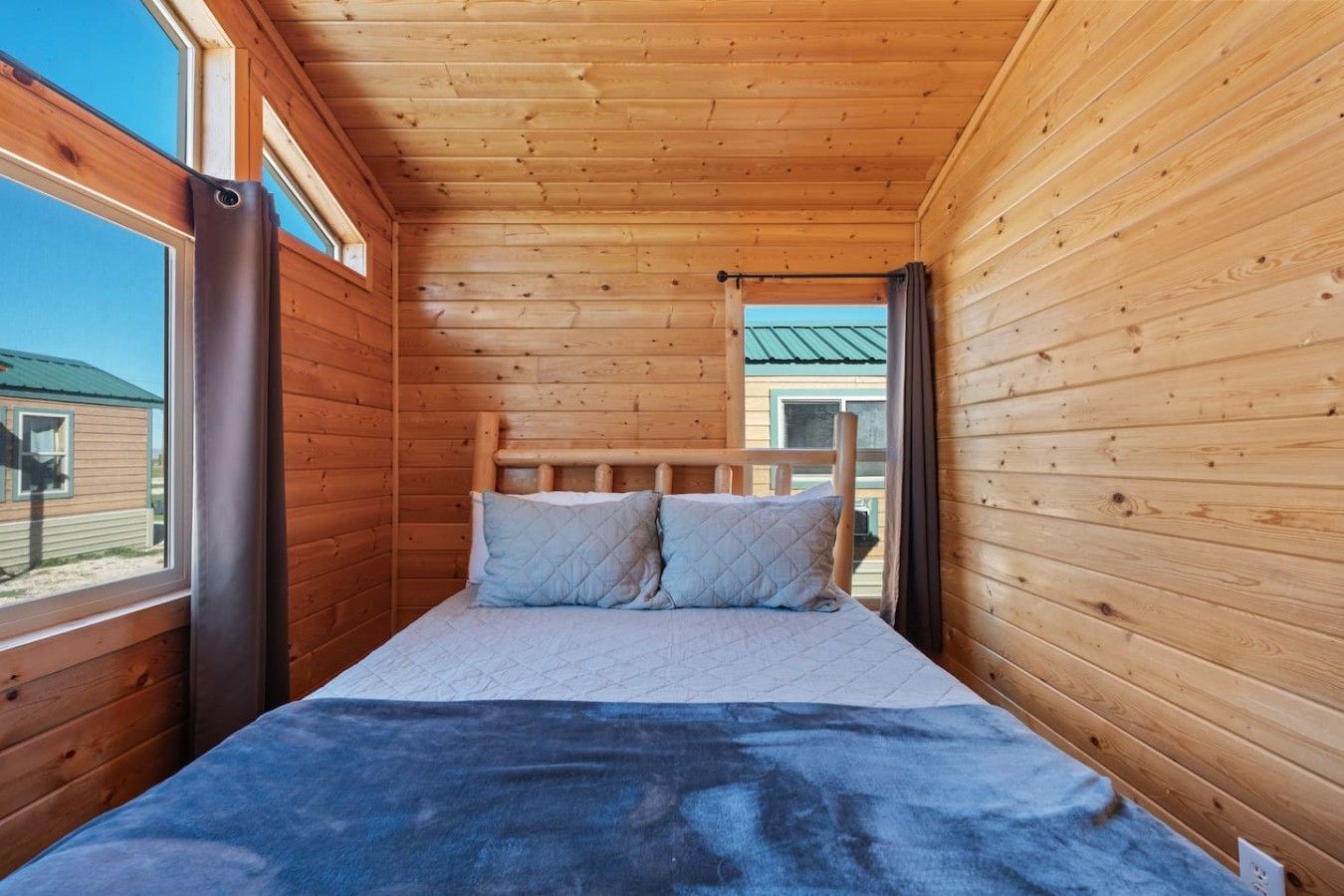 Una habitación de cabaña de madera con una cama, una ventana y una puerta.