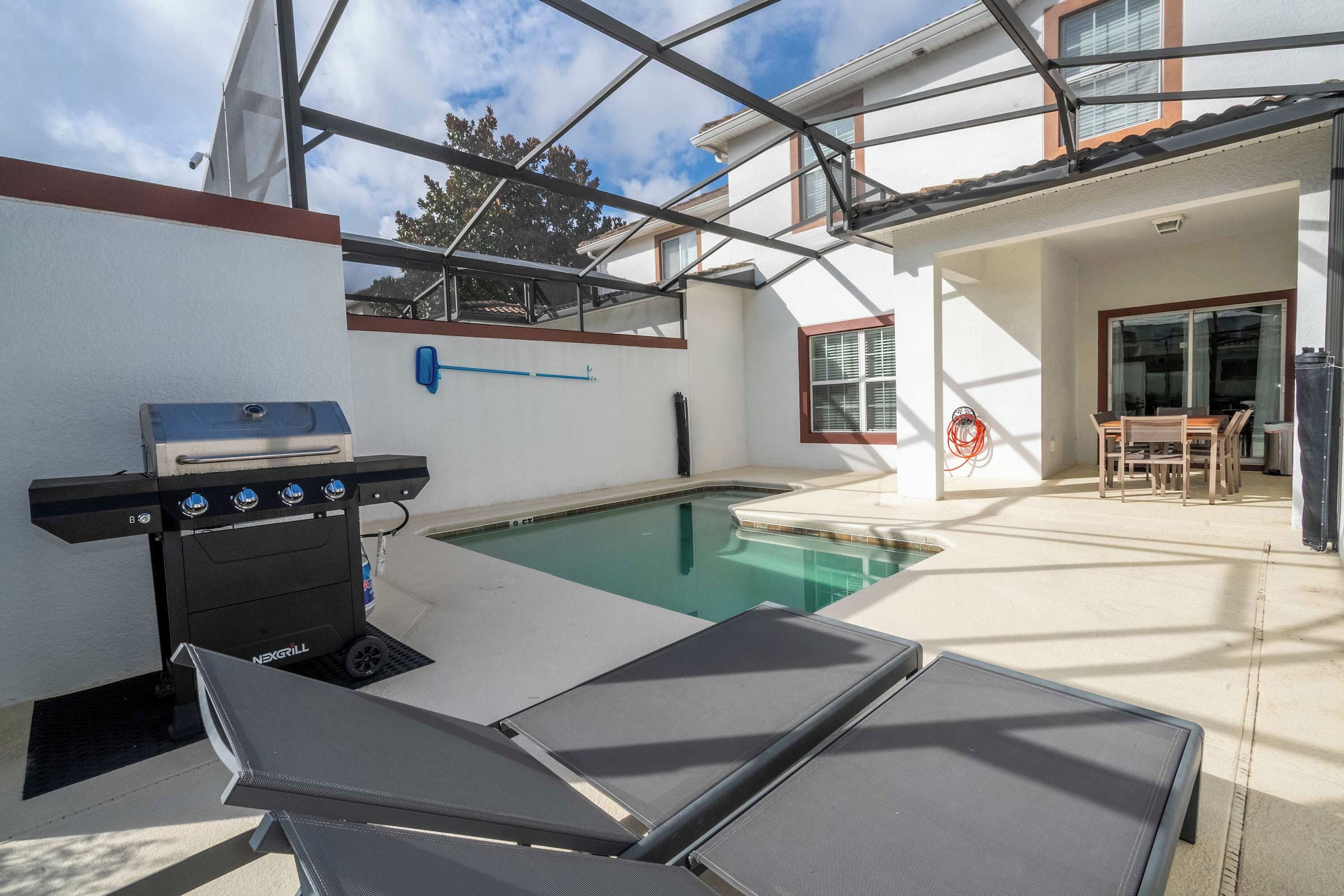 Ein Außenpoolbereich mit Grill und Liegestühlen.