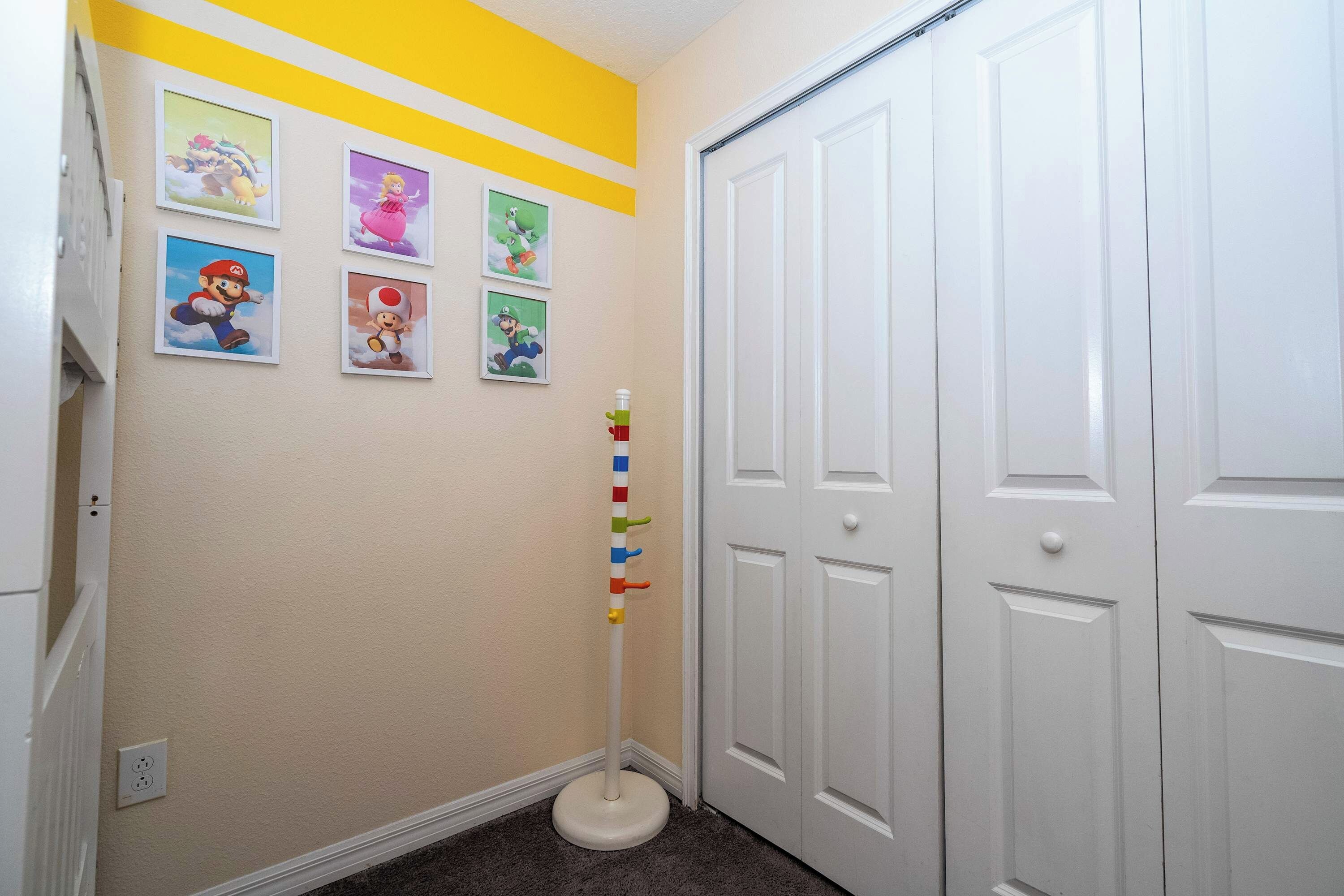 A hallway with a white door, a white closet, and a wall with framed video game character pictures.