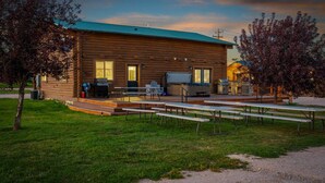 A log cabin with a porch, outdoor seating, and a grill.
