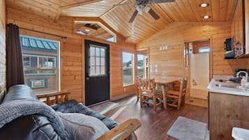 Ein Holzblockhaus-Interieur mit Essbereich, einer Couch und einer Küchenzeile.