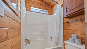A wooden cabin bathroom with a bathtub, toilet, and shower curtain. - #K305 Quail Cabin - AC, Fire Pit & BBQ! (Saint Charles)