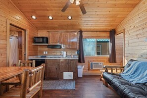A cabin interior with a kitchen, dining area, and a living room with a couch.