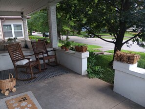A porch with two wooden chairs, a small table, and a basket. - Spacious Gem Sleeps 10, Centrally Located, & 10 Min From Downtown Louisville (New Albany)