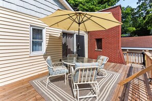 Une terrasse avec une table et des chaises, un parasol et une cheminée en briques.