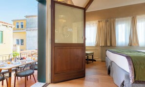 A room with a balcony, a bed, a dining table with chairs, and a window with curtains. - GRAND 3-BEDROOM VENETIAN PENTHOUSE WITH TERRACE & CAMPO VIEWS (Venezia)