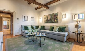 A living room with a sofa, two side tables, and a painting on the wall. - GRAND 3-BEDROOM VENETIAN PENTHOUSE WITH TERRACE & CAMPO VIEWS (Venezia)