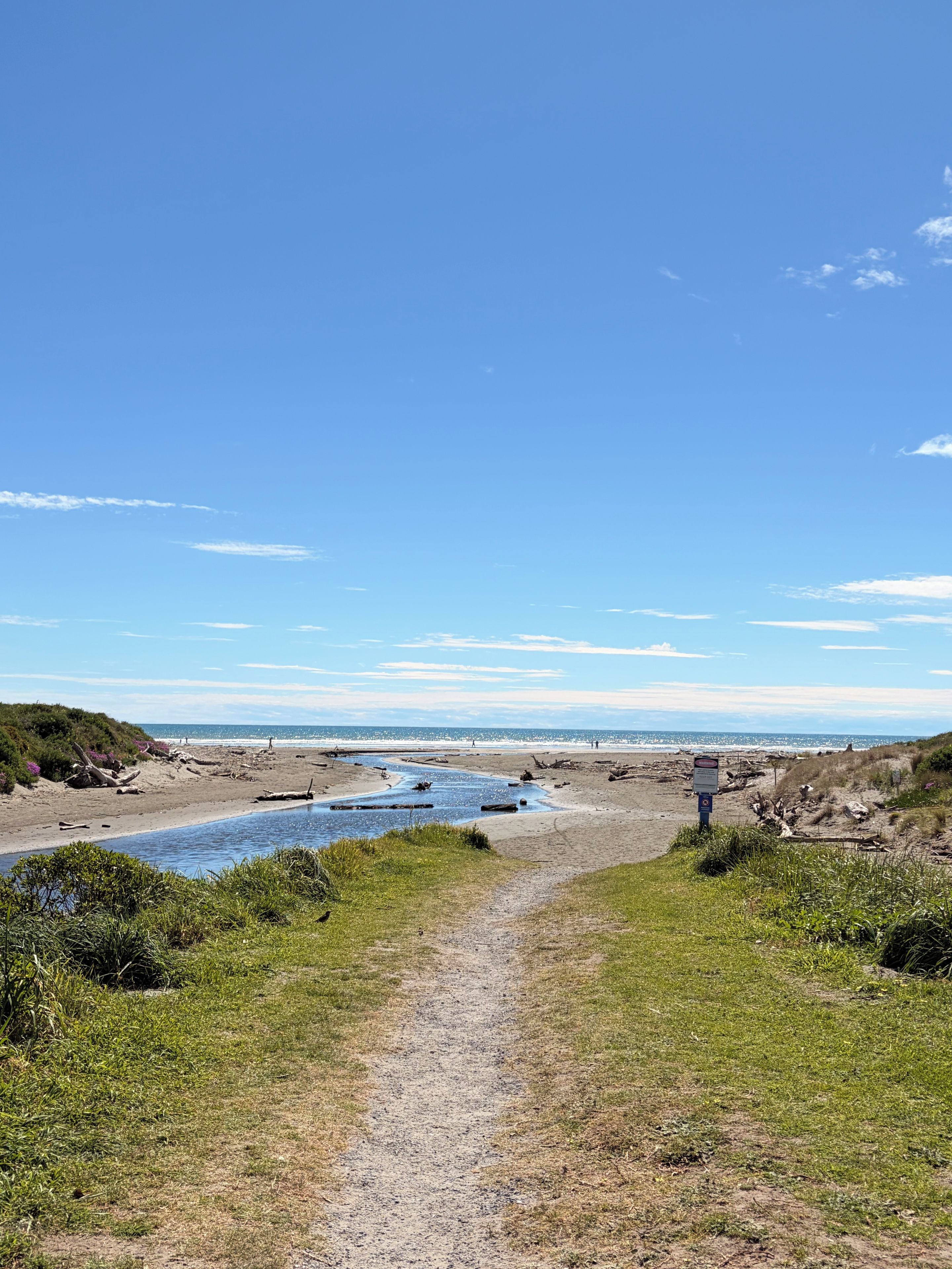 A coastal path leading to a beach with a clear sky.