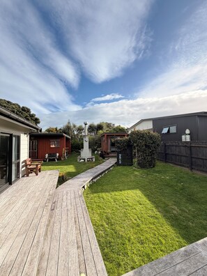 A backyard with a wooden deck, a concrete monument, and a fenced area.