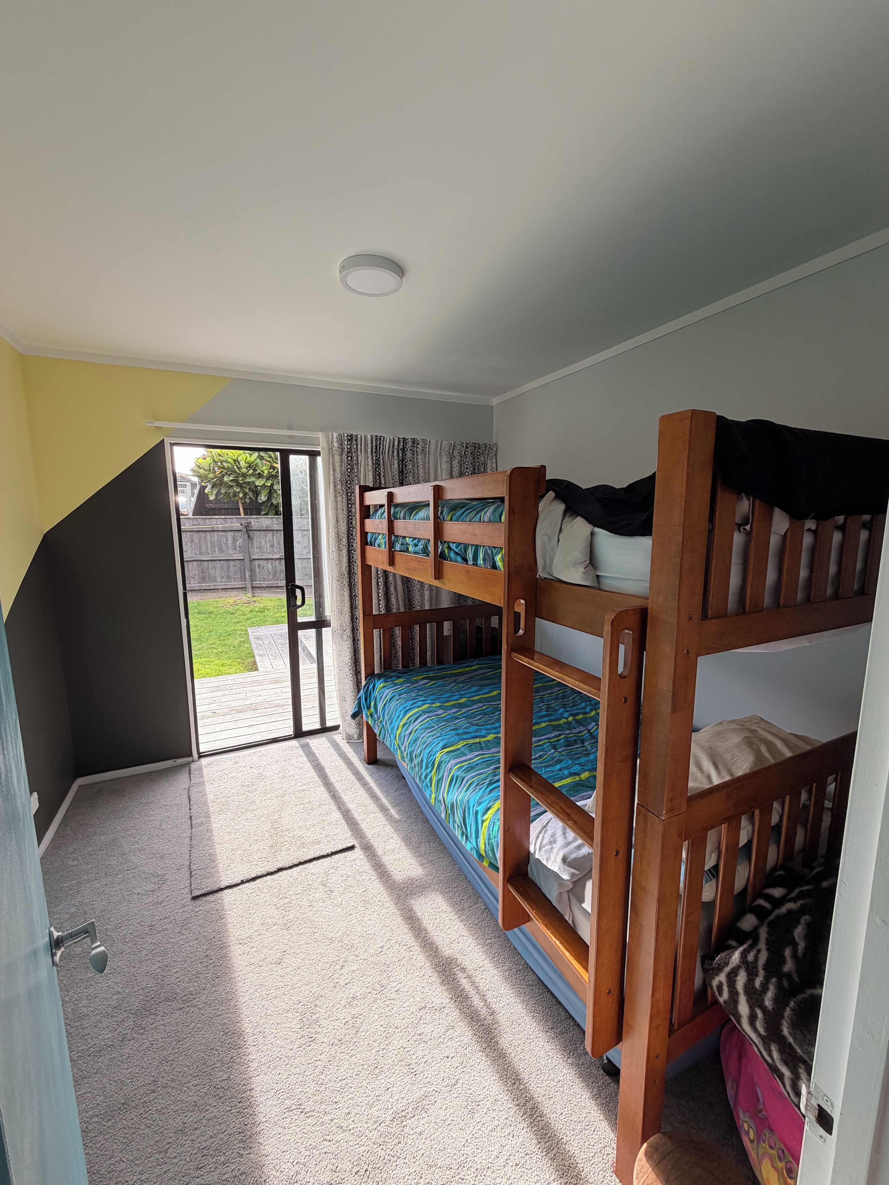A room with bunk beds, a door leading outside, and a carpeted floor.