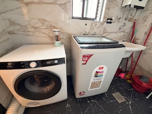 Lavadora y secadora combinadas de 12 kg, ubicadas en un baño con suelo de mármol y una ventana sobre el electrodoméstico.