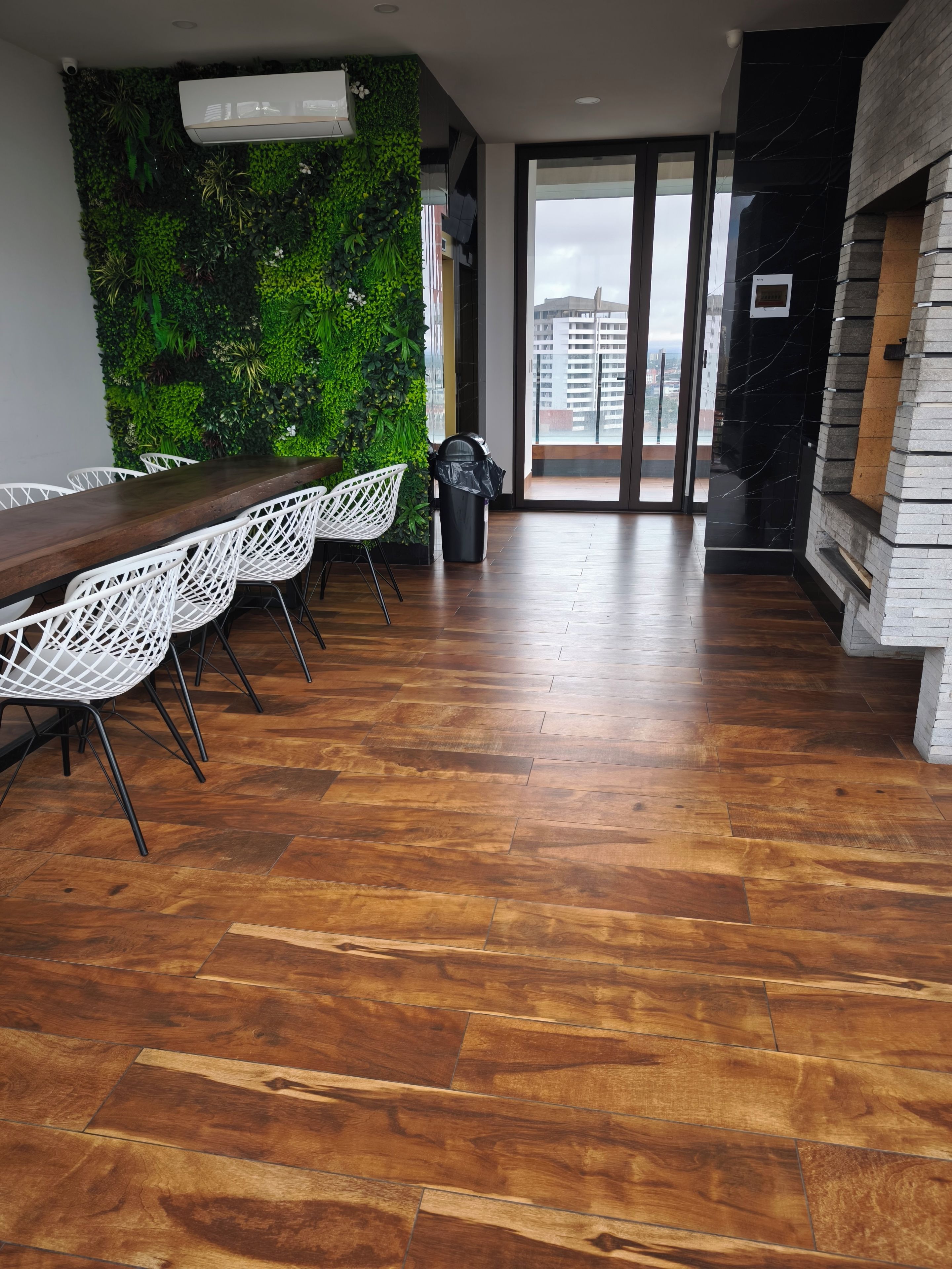 A modern interior with a wooden floor, white chairs, a long table, and a green wall.