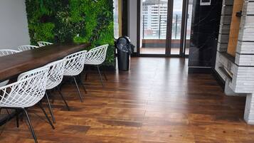 A modern interior with a wooden floor, white chairs, a long table, and a green wall.