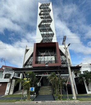 A modern building with a prominent vertical structure and a staircase leading to the entrance.