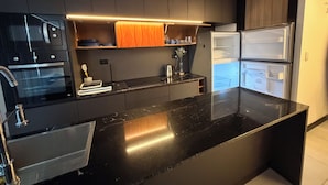 A modern kitchen with black countertops, stainless steel appliances, and wooden cabinets. - 518 RENT (Santa Cruz)