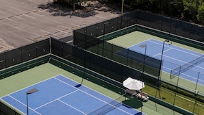 A tennis court with a net, surrounded by a fence, and palm trees nearby. - Cana Rock  (Punta Cana)