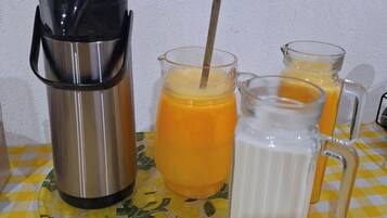 A stainless steel thermos, two glass mugs with straws, and a glass pitcher on a checkered tablecloth.