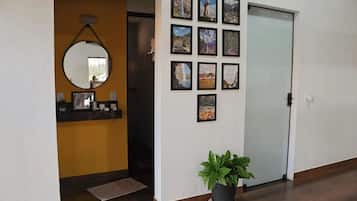 A hallway with a mirror, a potted plant, and a wall adorned with framed pictures.