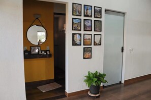 Un pasillo con un espejo, una planta en maceta y una pared decorada con cuadros.