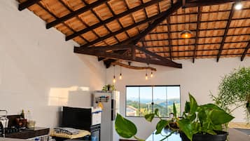 A kitchen with a large window, a ceiling with exposed beams, and a view of the countryside.