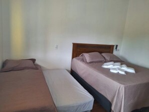 A room with two beds, each with a wooden headboard, and a small bedside table. - Chalés do Popô na Canastra (São Roque de Minas)
