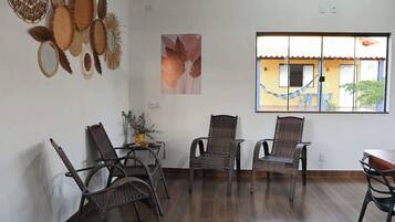 A room with wicker chairs, a small table with a vase, and a window with a view of buildings.