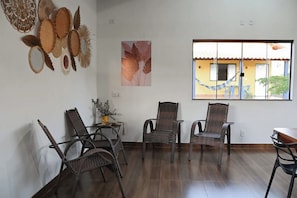 A room with wicker chairs, a small table with a vase, and a window with a view of buildings.