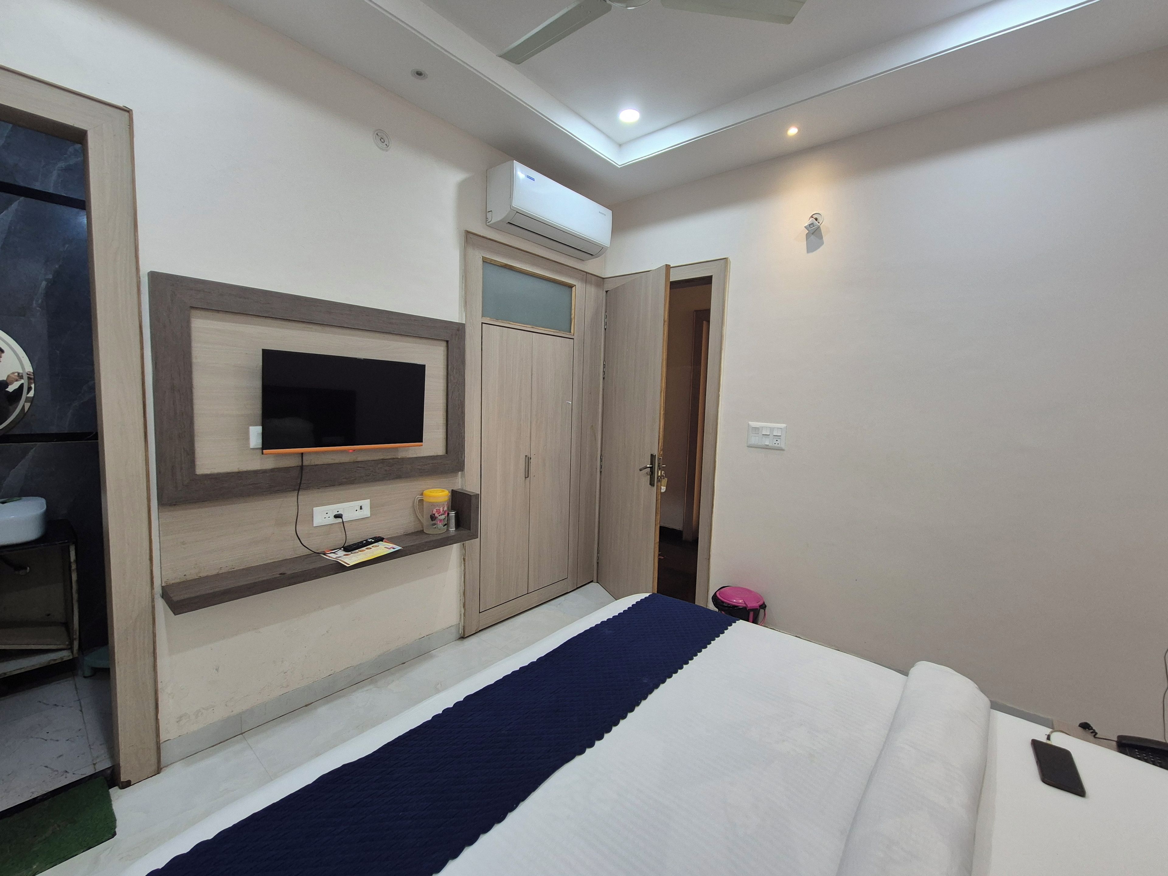 Un dormitorio con cama, televisión montada en la pared, armario y aire acondicionado.
