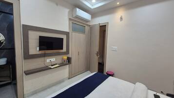 Un dormitorio con cama, televisión montada en la pared, armario y aire acondicionado.