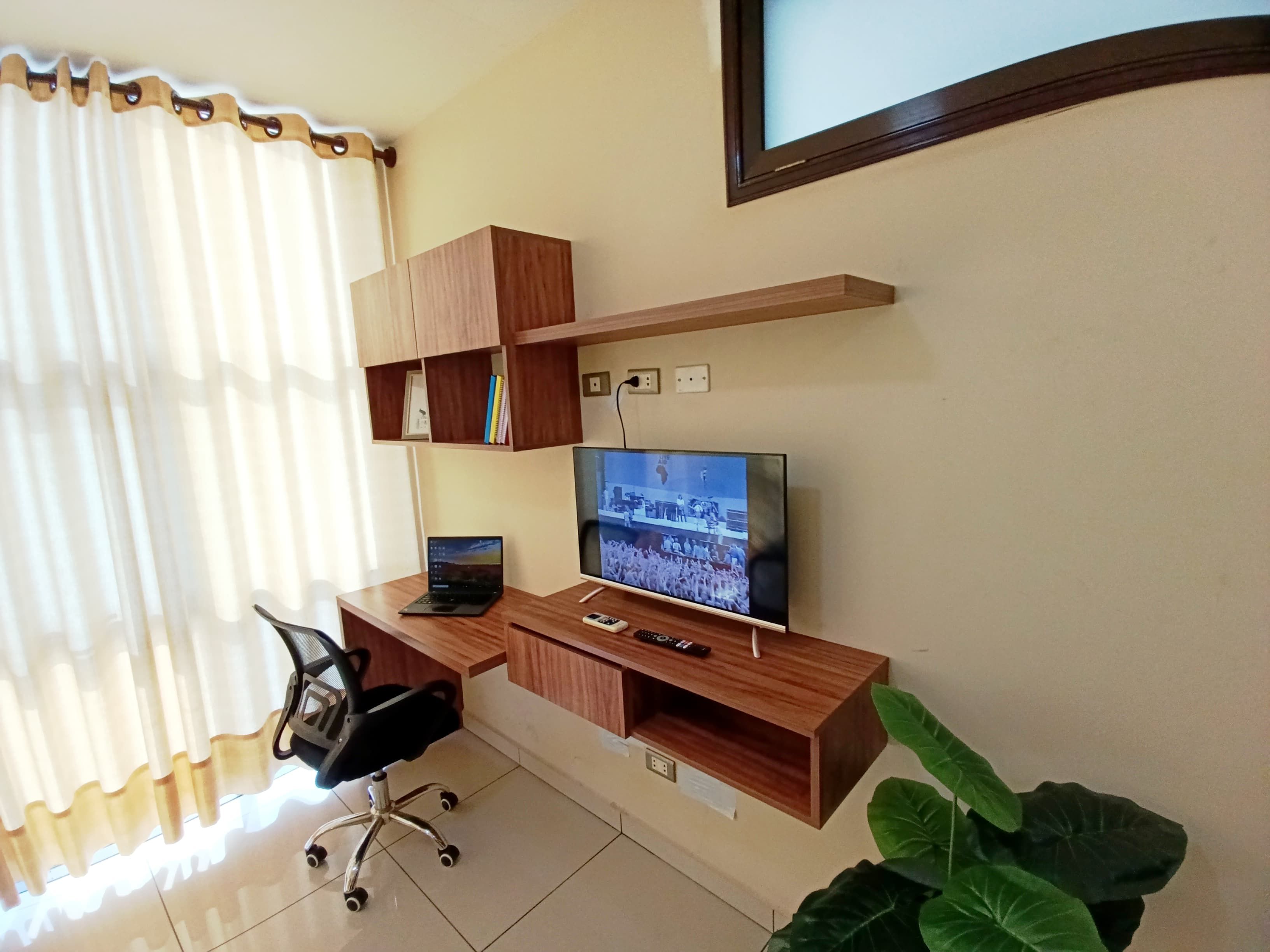 A modern office space with a desk, chair, computer, and television.