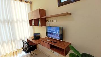 A modern office space with a desk, chair, computer, and television.