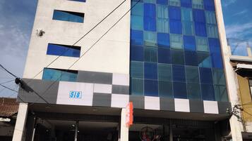 Un edificio de varios pisos con un amplio frente de vidrio, una tienda visible en la planta baja y un cielo despejado al fondo.