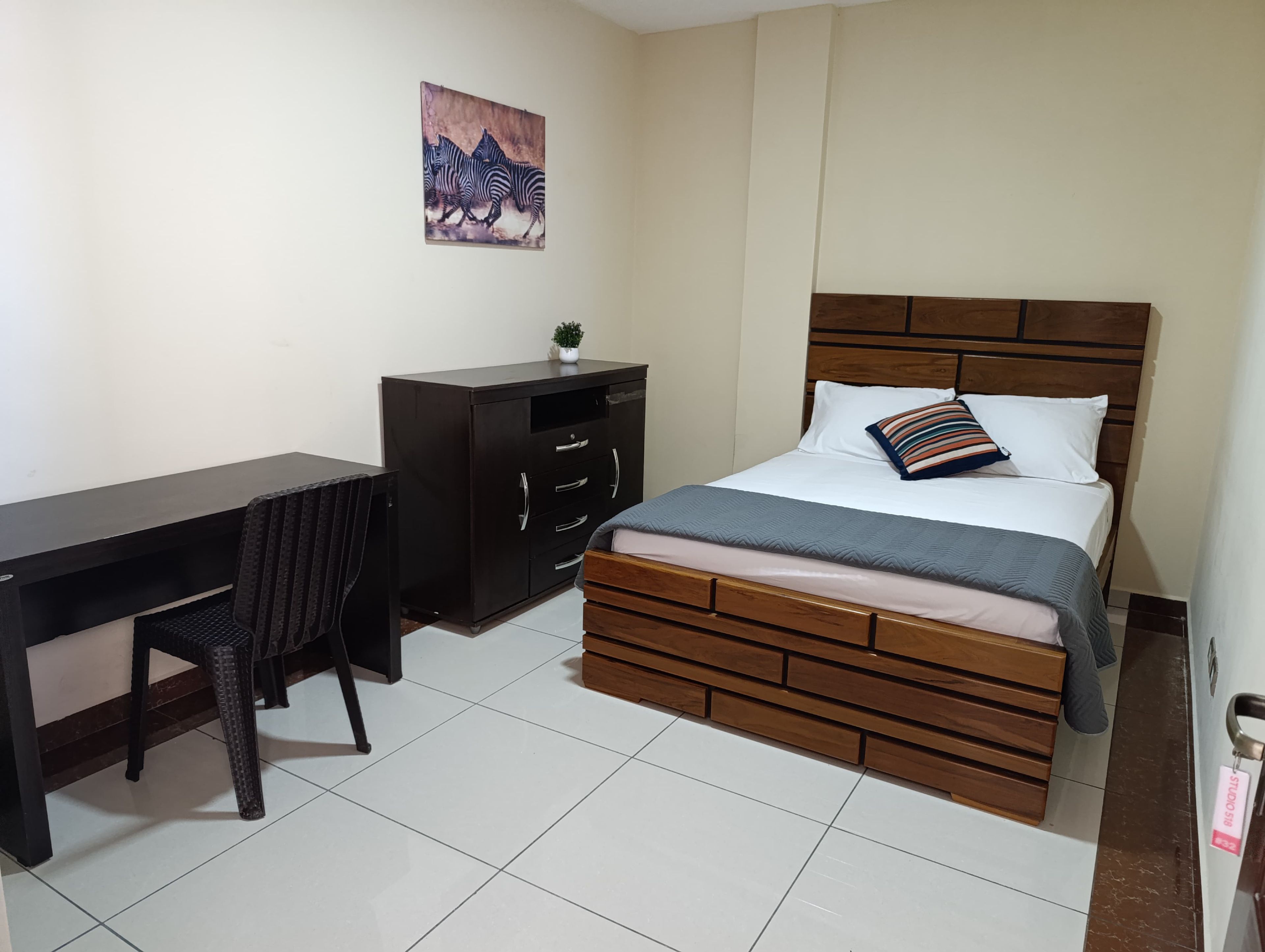 Un dormitorio con cama, escritorio y silla.