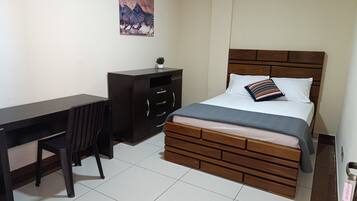 Un dormitorio con cama, escritorio y silla.