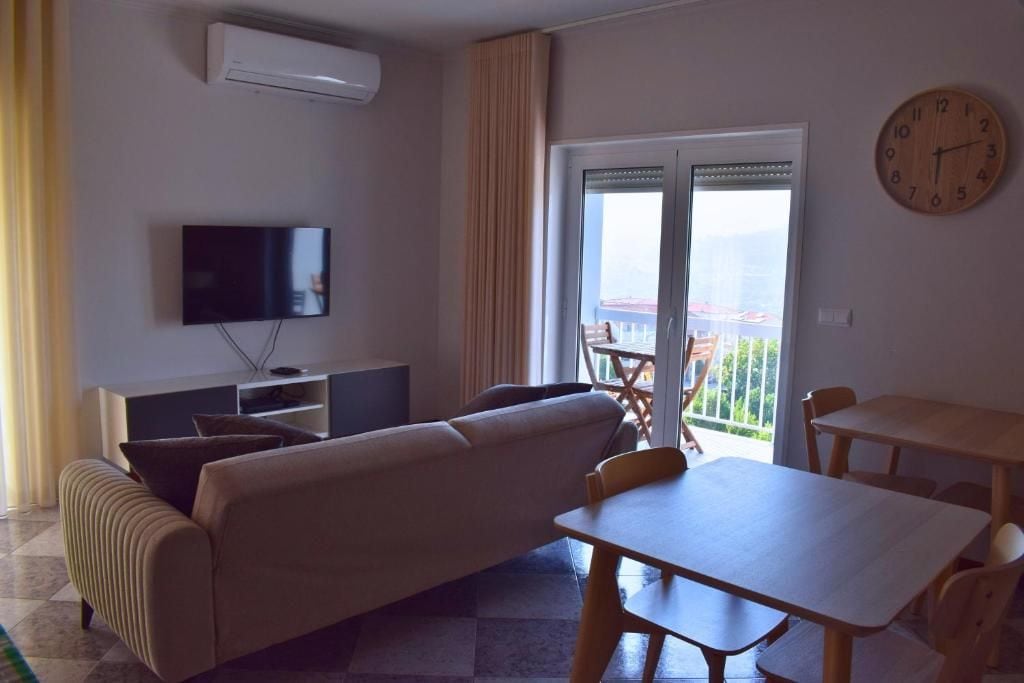Una sala de estar con sofá, televisión y una mesa de comedor con sillas.