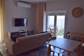 Una sala de estar con sofá, televisión y una mesa de comedor con sillas.