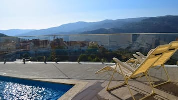 Un espace piscine aménagé sur le toit, avec des chaises longues et une vue sur le paysage environnant.