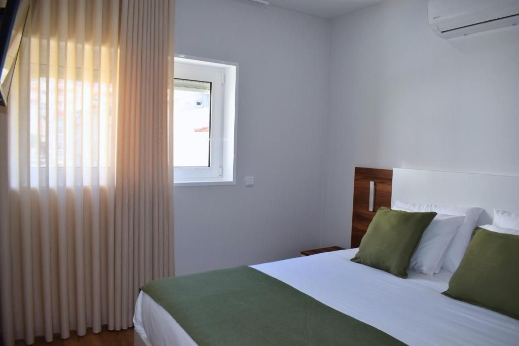 Una habitación de hotel con cama, ventana y aire acondicionado.
