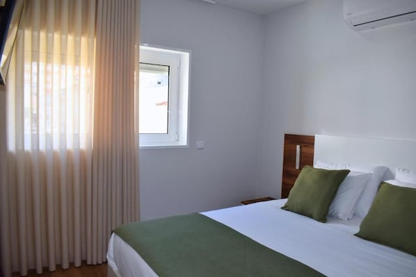 Una habitación de hotel con cama, ventana y aire acondicionado.