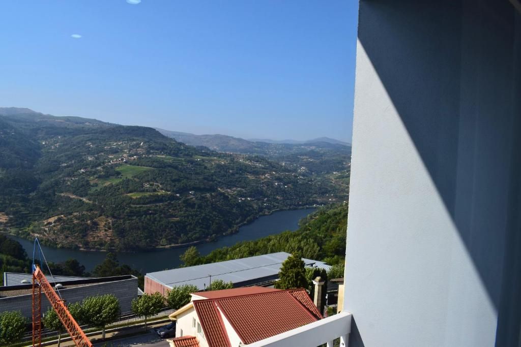 Vista de um vale com um lago, rodeado por colinas e edifícios.