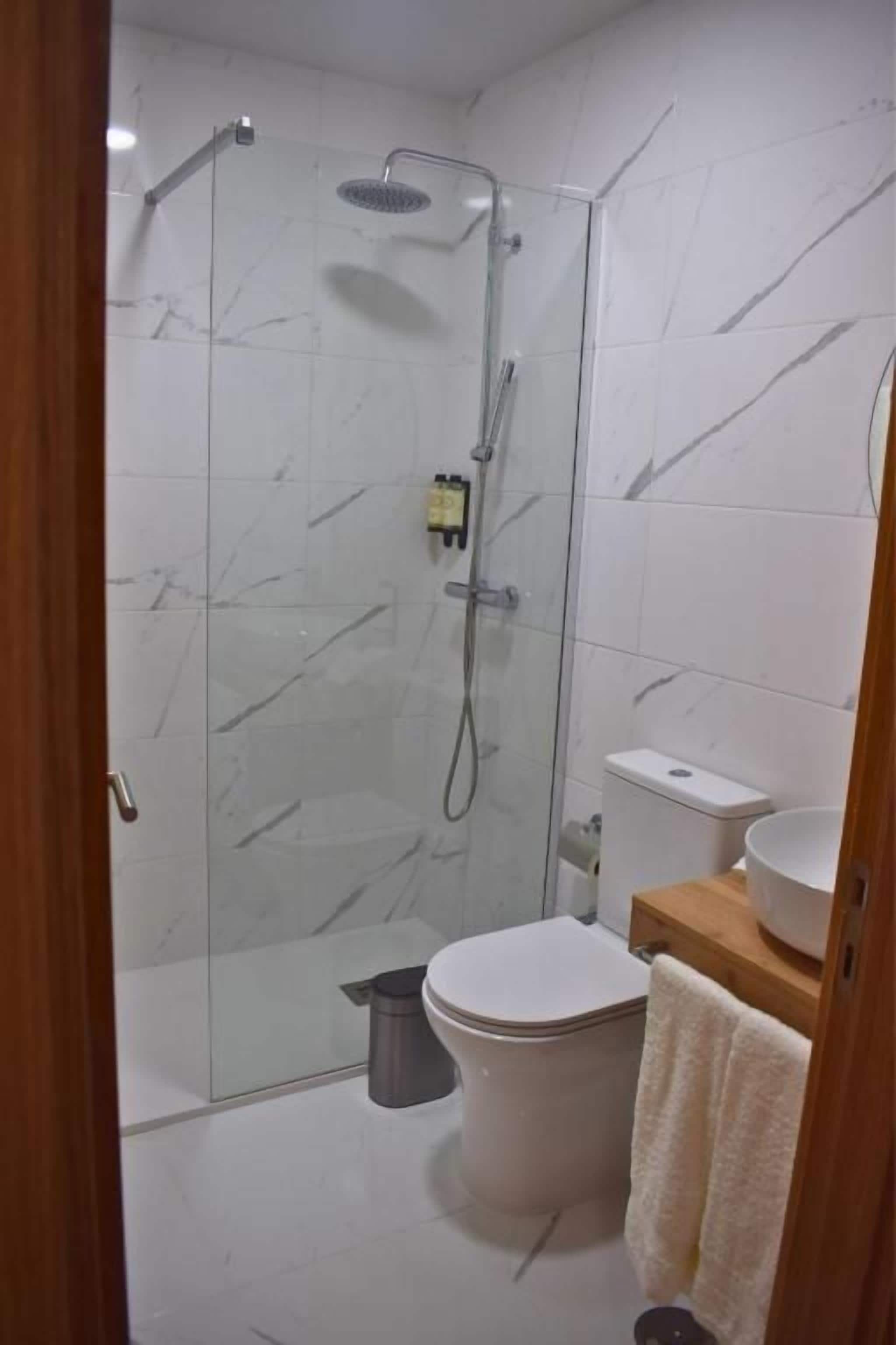 Un baño con ducha de vidrio, inodoro y lavamanos.